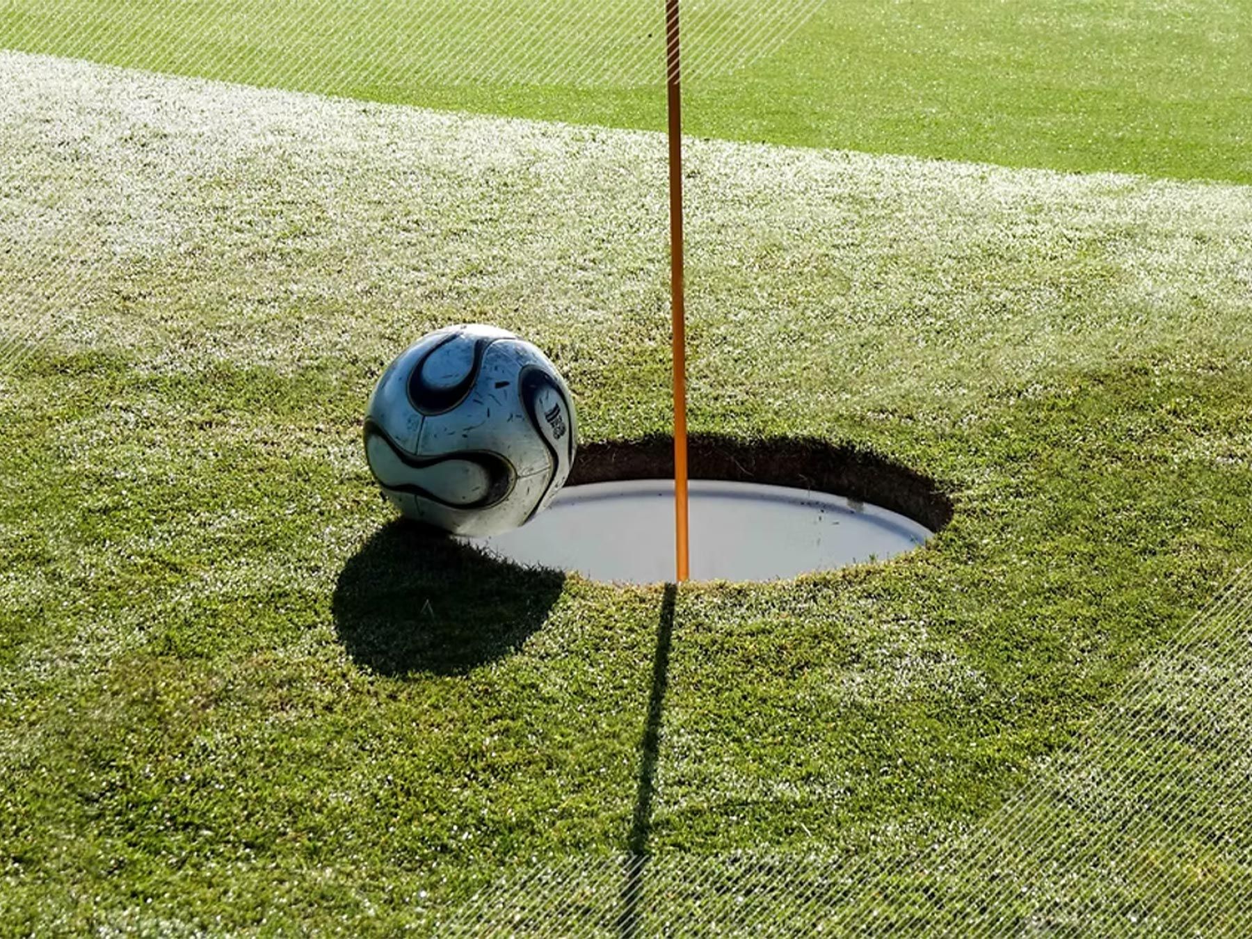 Soccer ball resting beside a FootGolf cup