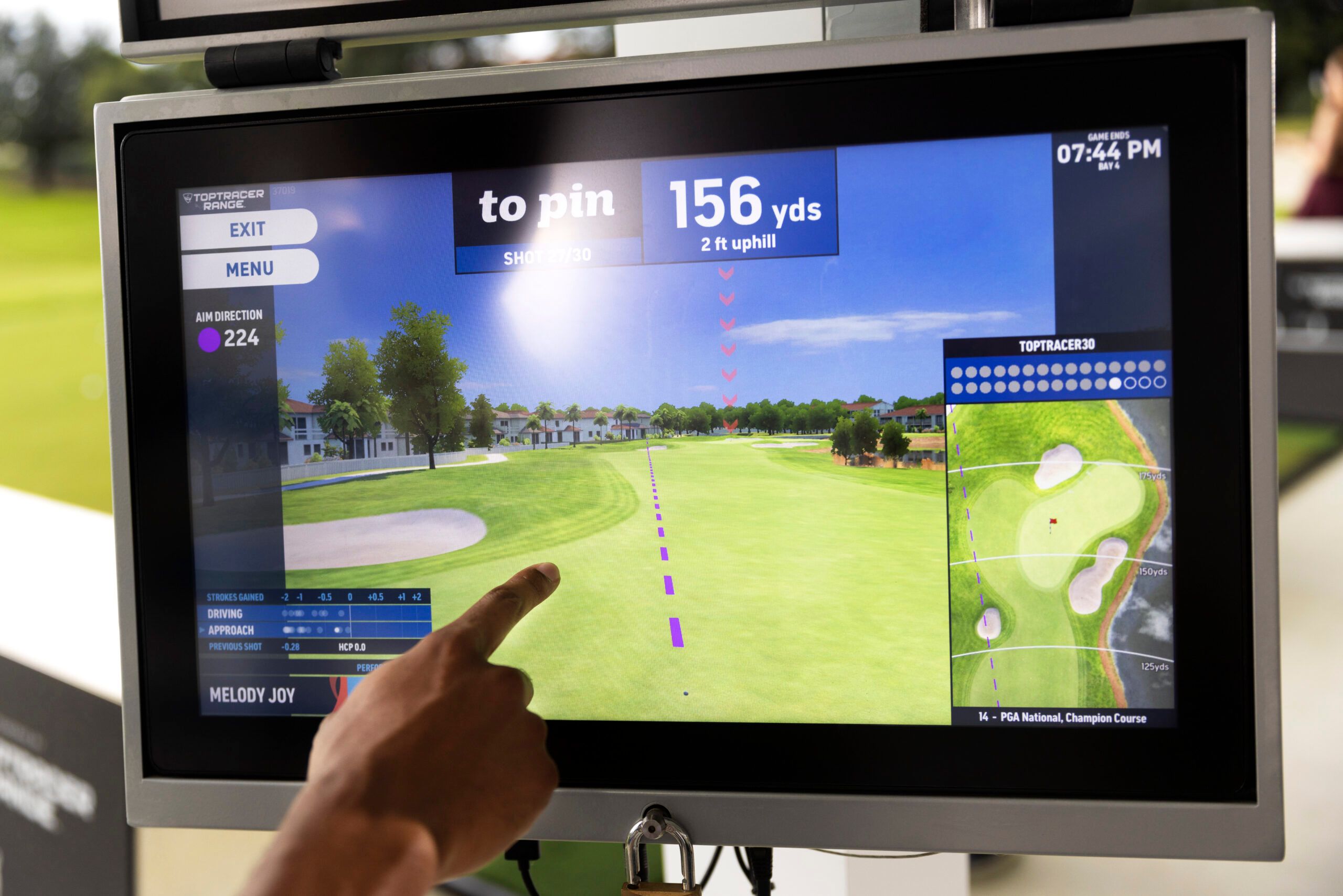 Golfer checking shot data on a Toptracer screen